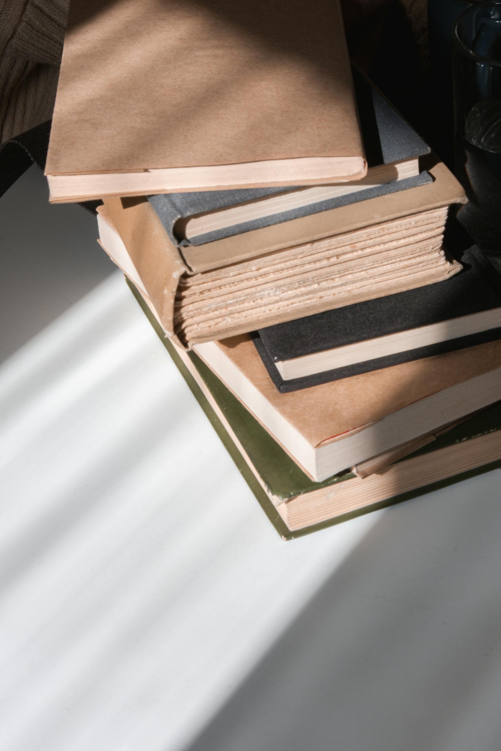 A stack of books casting interesting shadows on a surface, creating a cozy reading ambiance.